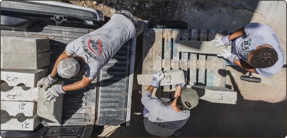 Overhead view of three team members loading cast concrete modules into a pickup truck