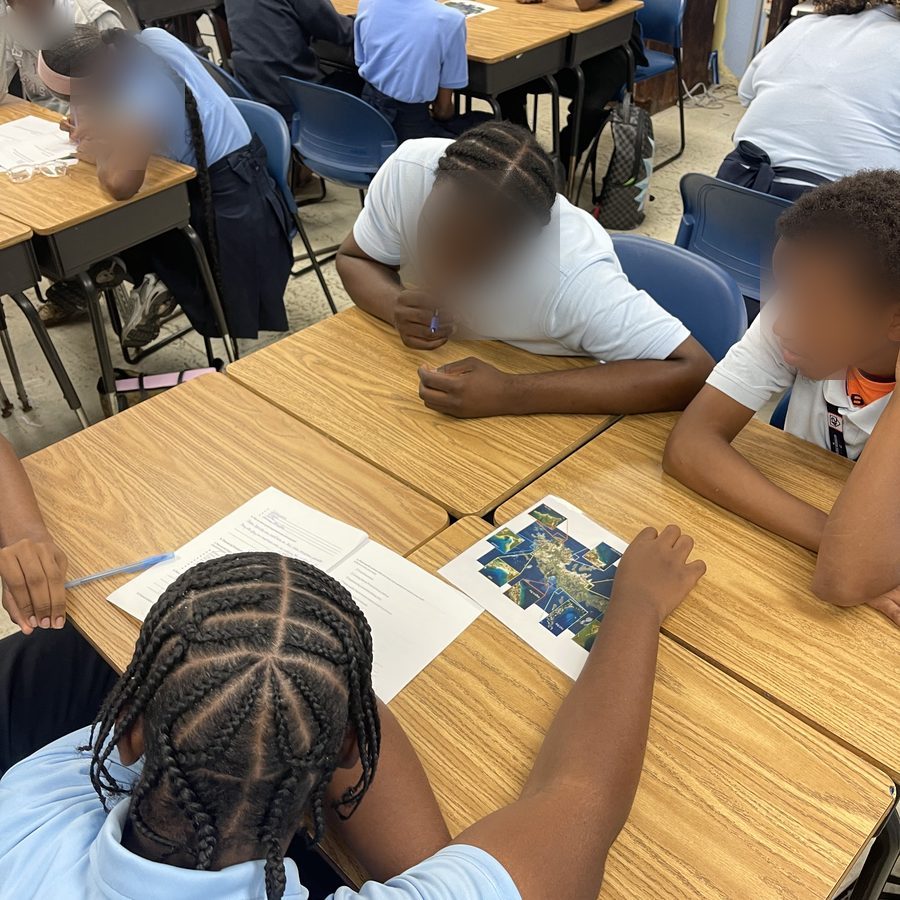 Students at their desks studying printed underwater reef photographs