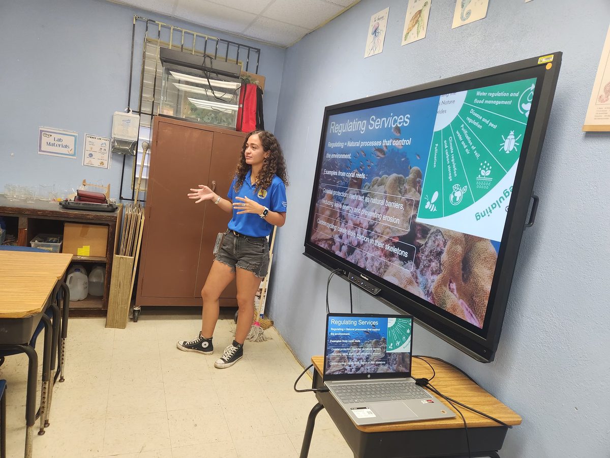 A Reef Response staff member teaching a Corals in the Classroom lesson on the ecosystem services coral reefs provide